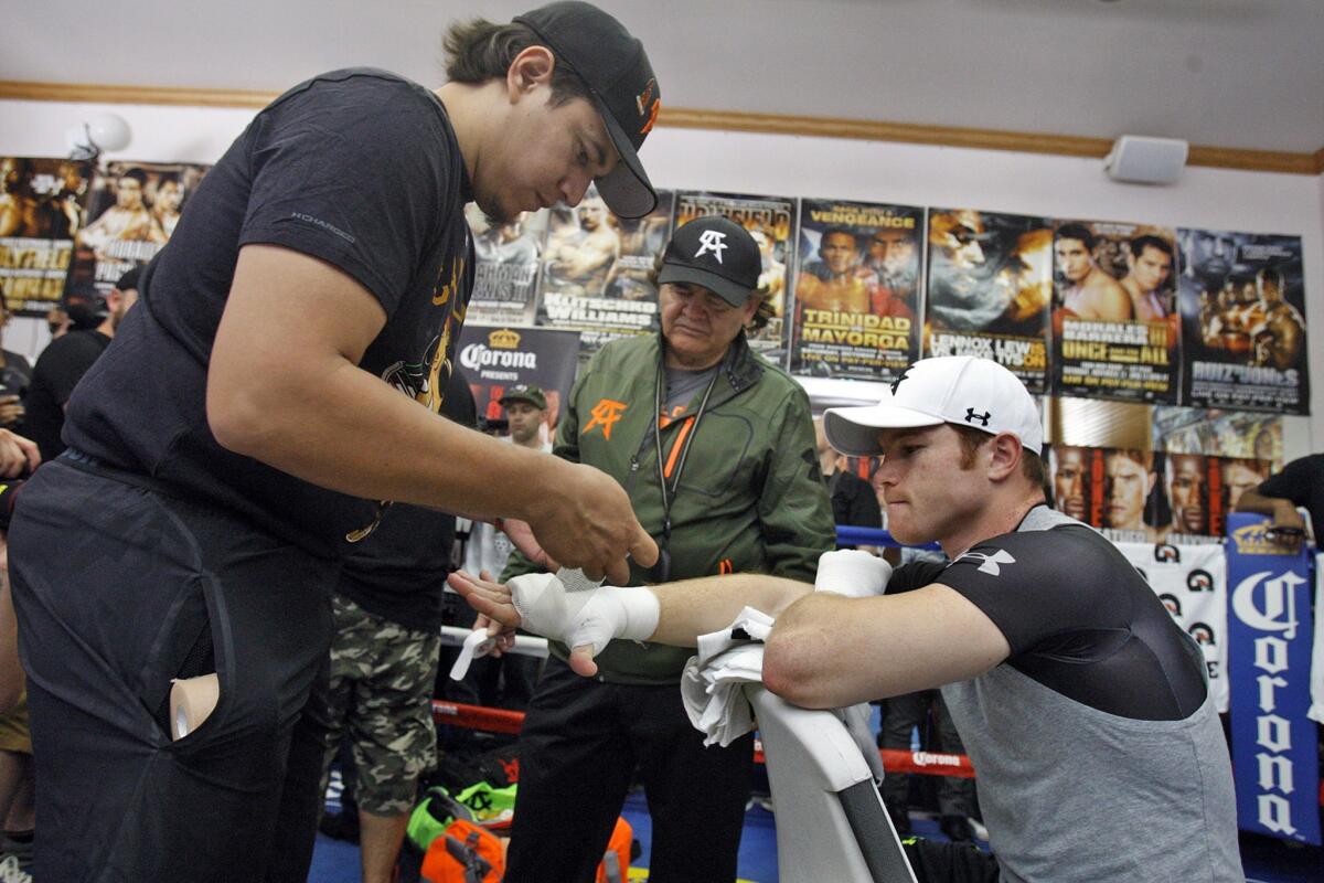 Eddy Reynoso, left, tapes up Saul "Canelo" Alvarez's hands during a training session in Big Bear as Reynoso's father, Chepo, looks on. The Reynosos have worked closely with Alvarez throughout his entire boxing career.