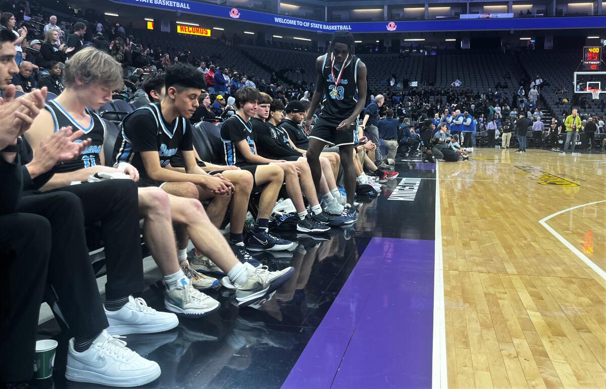 Buena boys' basketball players sit on the bench after receiving their runner-up medals at the Division III state title game.