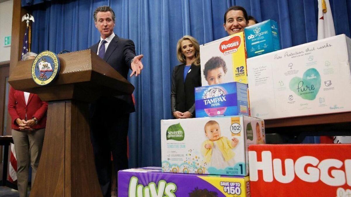 Gov. Gavin Newsom gestures towards boxes of tampons and diapers after proposing to eliminate the state sales tax on such products in a Sacramento news conference on May 7.