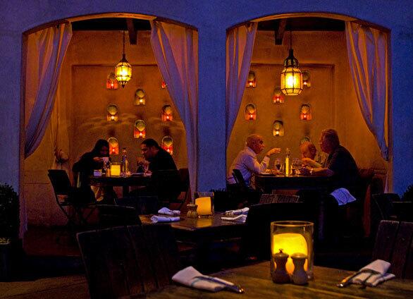 The dining area includes white-curtained cabanas, giving it a desert encampment look.