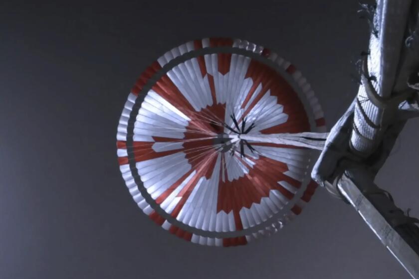 This image from video made available by NASA shows the parachute deployed during the descent of the Mars Perseverance rover as it approaches the surface of the planet on Thursday, Feb. 18, 2021. Systems engineer Ian Clark used a binary code to spell out “Dare Mighty Things” in the orange and white strips of the 70-foot (21-meter) parachute. He also included the GPS coordinates for the mission's headquarters at the Jet Propulsion Laboratory in Pasadena, Calif. (NASA/JPL-Caltech via AP)