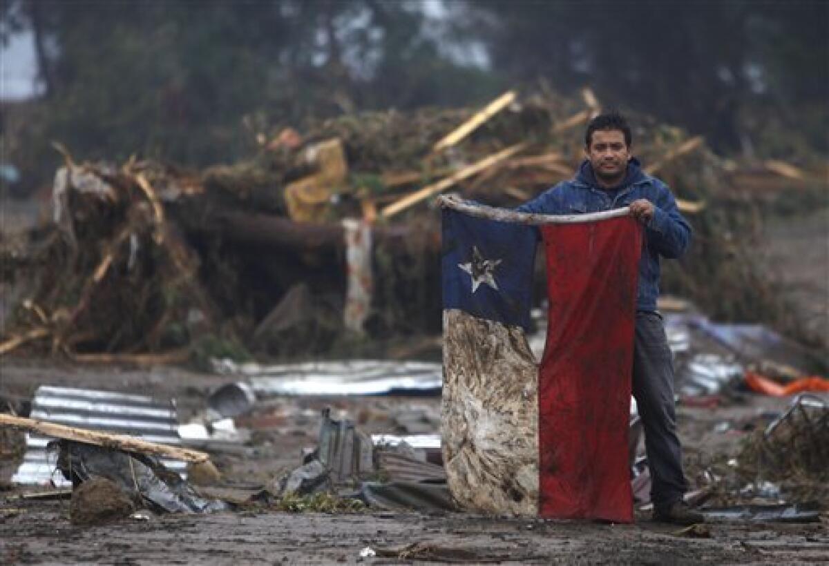 A man holds up a Chilean flag in a flooded area after an earthquake in Pelluhue, some 322 kms, about 200 miles, southwest of Santiago, Sunday, Feb. 28, 2010. A 8.8-magnitude earthquake hit Chile early Saturday. (AP Photo/Roberto Candia)