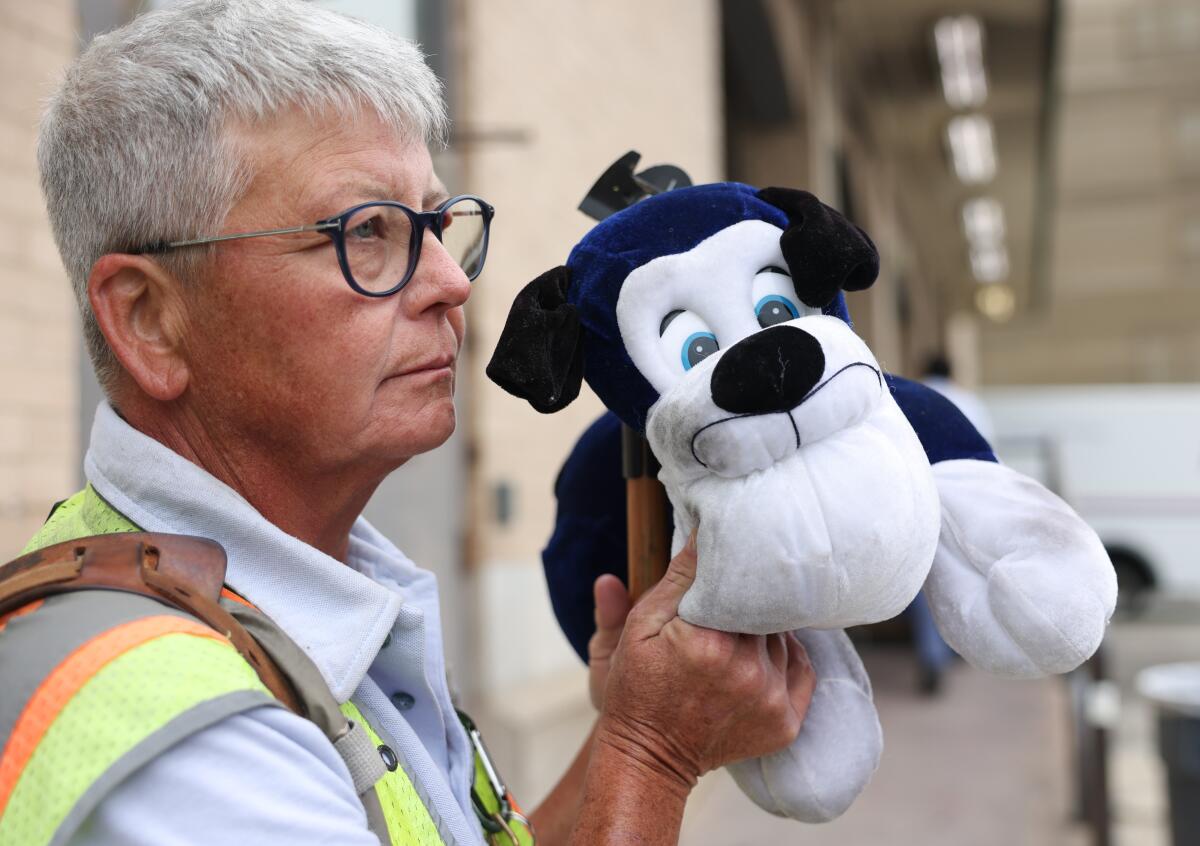 Mail carrier Holly Ahlborn holds up a stuffed dog.