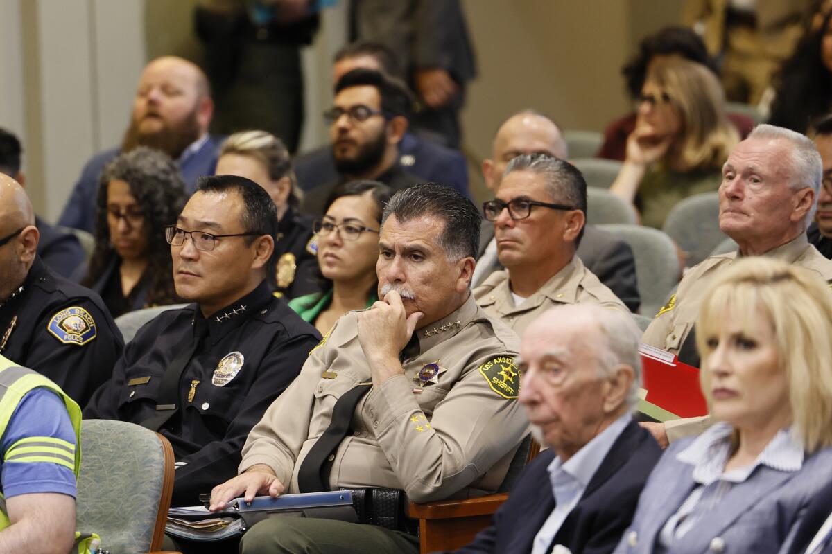 Dominic Choi and Robert Luna sit listening in an audience.