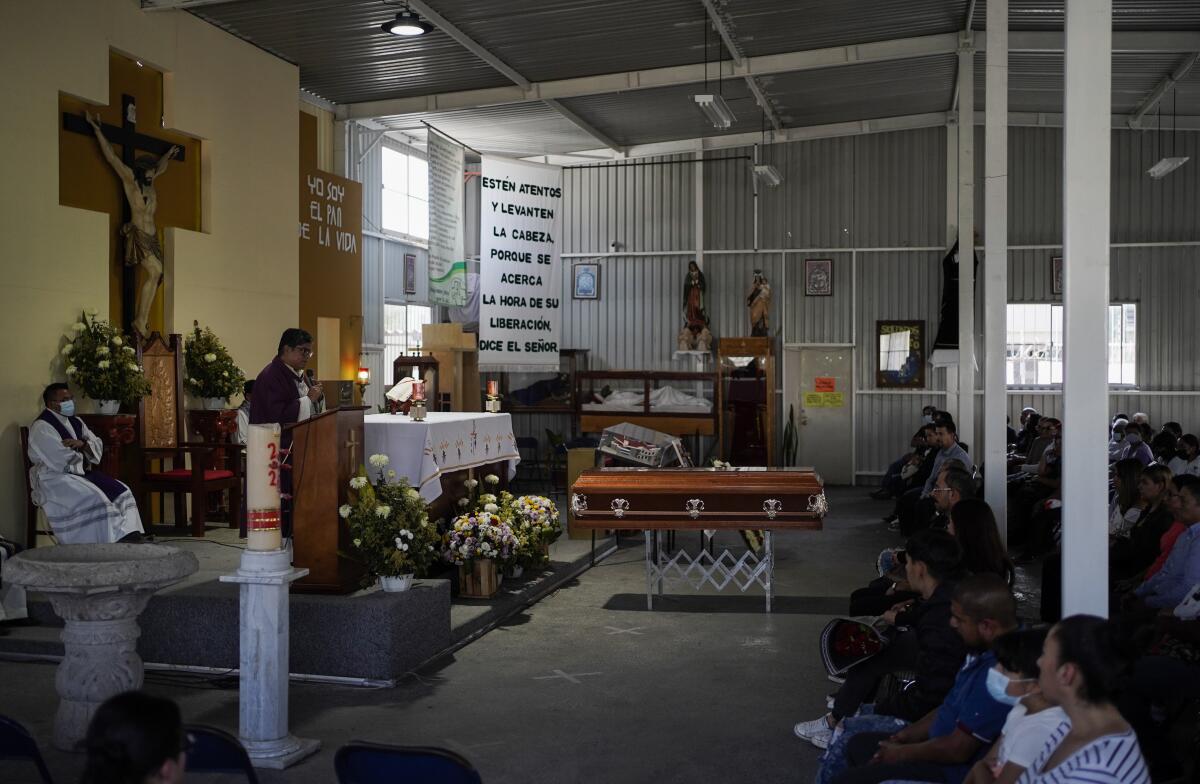 People sit in a church before a casket 