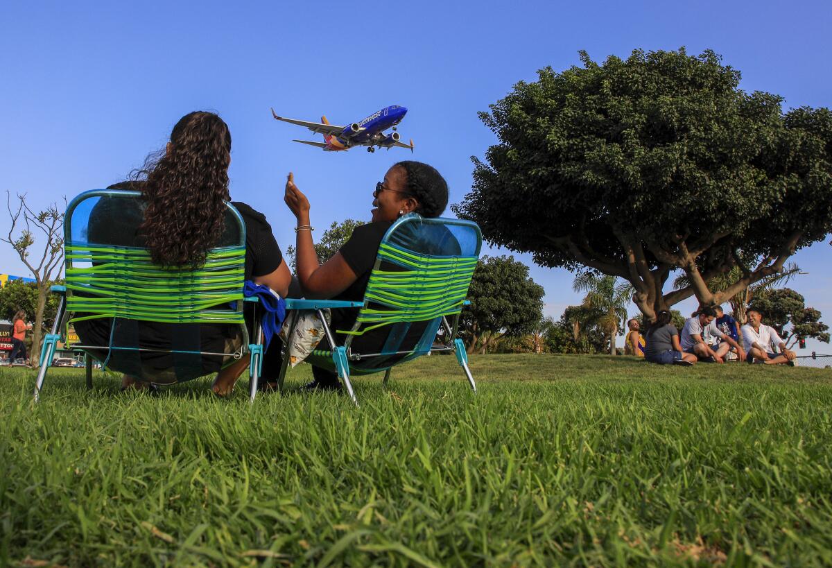People watch planes land at LAX from a park in Westchester.