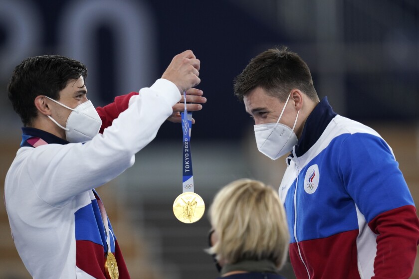 Russian Olympic Committee gymnast Artur Dalaloyan, left, places a gold medal around the neck of teammate Nikita Nagornyy