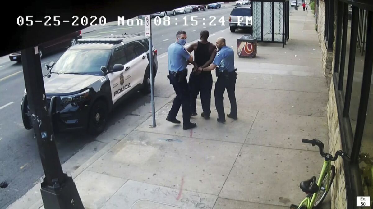 Two police officers escorting a handcuffed George Floyd to a police vehicle in an image from a video taken May 25, 2020.