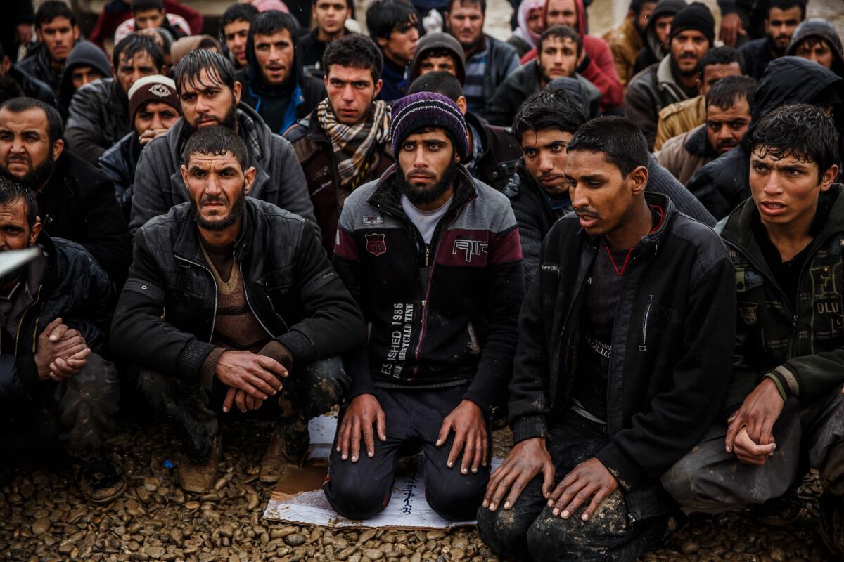 Men kneel silently as they wait for their names to be called by Iraqi police screeners south of Mosul. (Marcus Yam / Los Angeles Times)