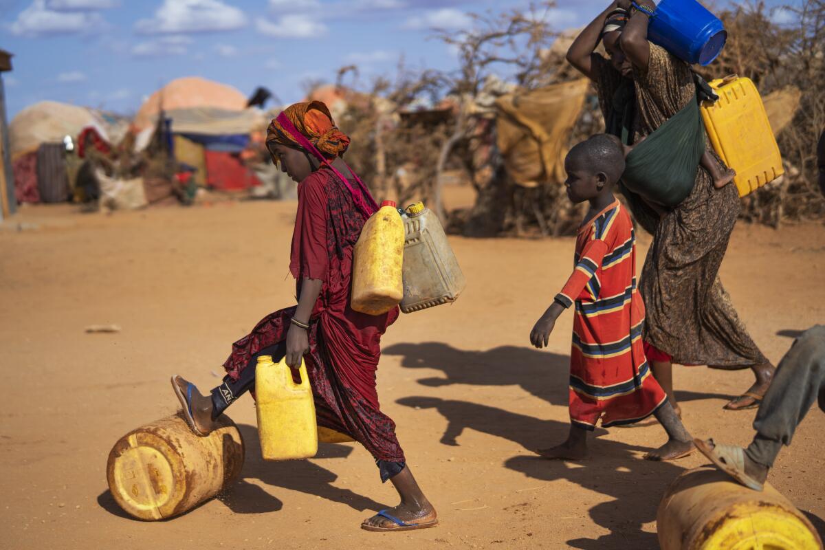Woman and children carrying water containers at a camp for displaced people in Somalia