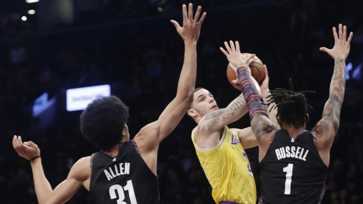 Lakers' Lonzo Ball looks to pass the ball away from Brooklyn's D'Angelo Russell (1) and Jarrett Allen (31).