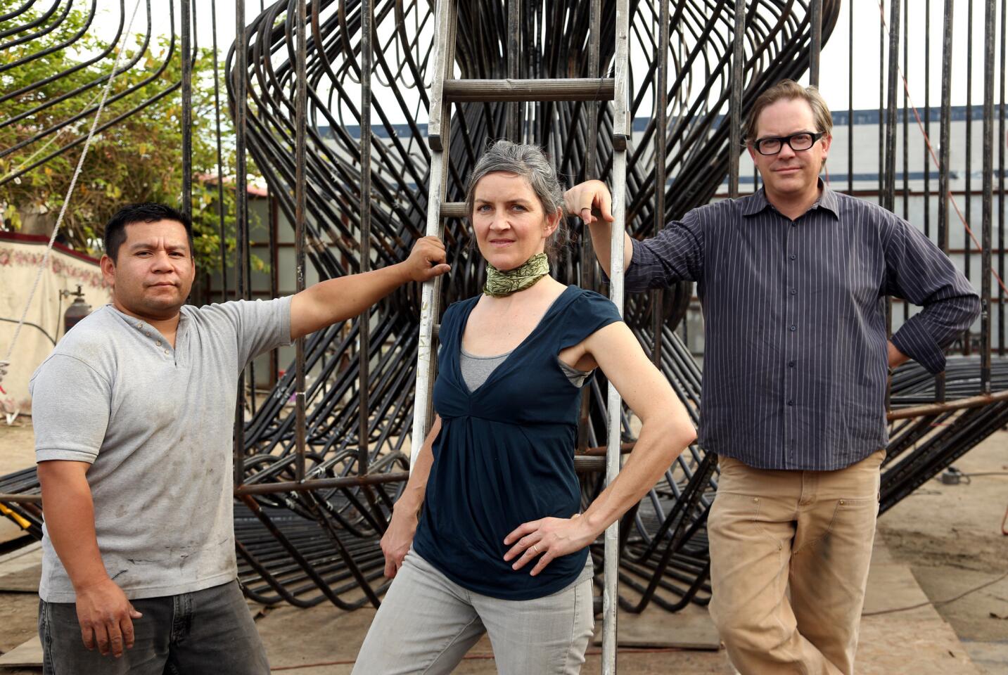 Lead welder Edwin Ramirez, left, artist Jenna Didier and architect Warren Techentin stand in front of "La Cage aux Folles," a work in progress that will go on exhibit in front of Materials & Applications in April.