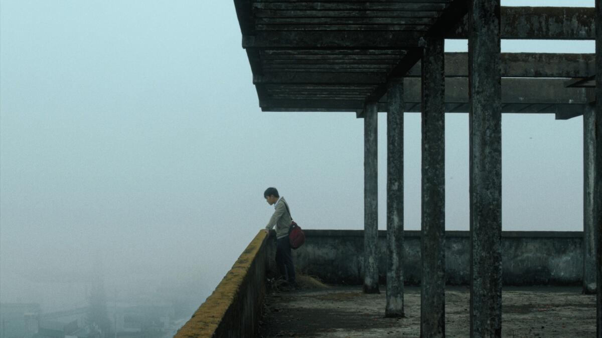 A man peers down from a building rooftop.
