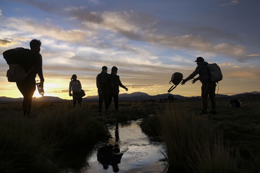 Migrants cross a stream after crossing into Chile from Bolivia, near Colchane, Chile, Thursday, Dec. 9, 2021. (AP Photo/Matias Delacroix)