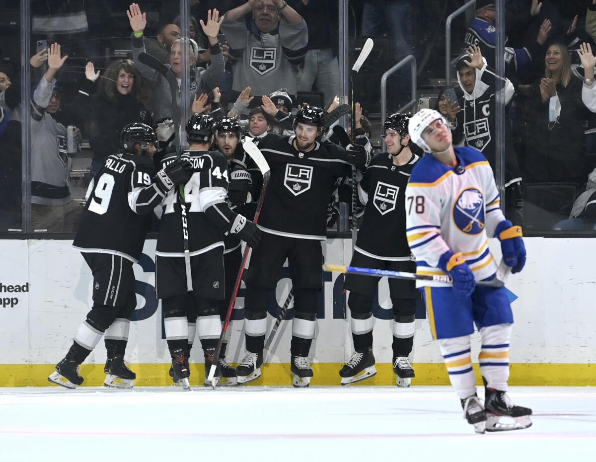 Kings players celebrate a third-period goal as Buffalo Sabres defenseman Jacob Bryson skates back to the bench.