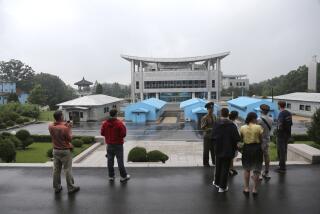 FILE - Visitors look toward the South Korean building as North Korean soldiers guard the truce village of Panmunjom at the Demilitarized Zone (DMZ) which separates the two Koreas in Panmunjom, North Korea, July 22, 2013. An American has crossed the heavily fortified border from South Korea into North Korea, the American-led U.N. Command overseeing the area said Tuesday, July 18, 2023, amid heightened tensions over North Korea's nuclear program. (AP Photo/Wong Maye-E, File)