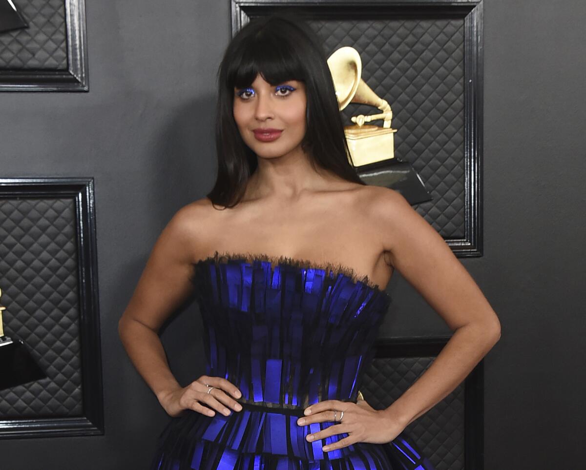 A woman stands with her hands on her hips in a blue dress