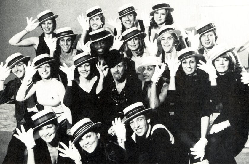 A black and white photo of a large group of people tipping their hats