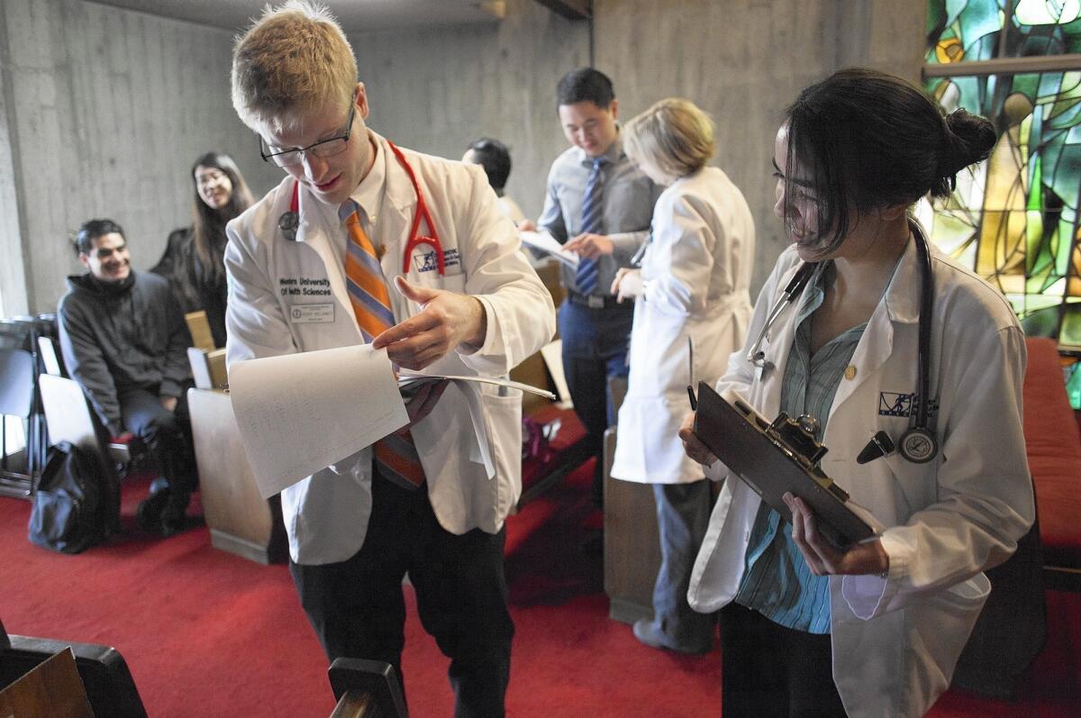 Medical students Cody Delaney, left, and Theresa Price, both from Western University of Health Science in Pomona, look over a patient's paperwork at a free clinic on Saturday, held at United Methodist Church in Garden Grove.