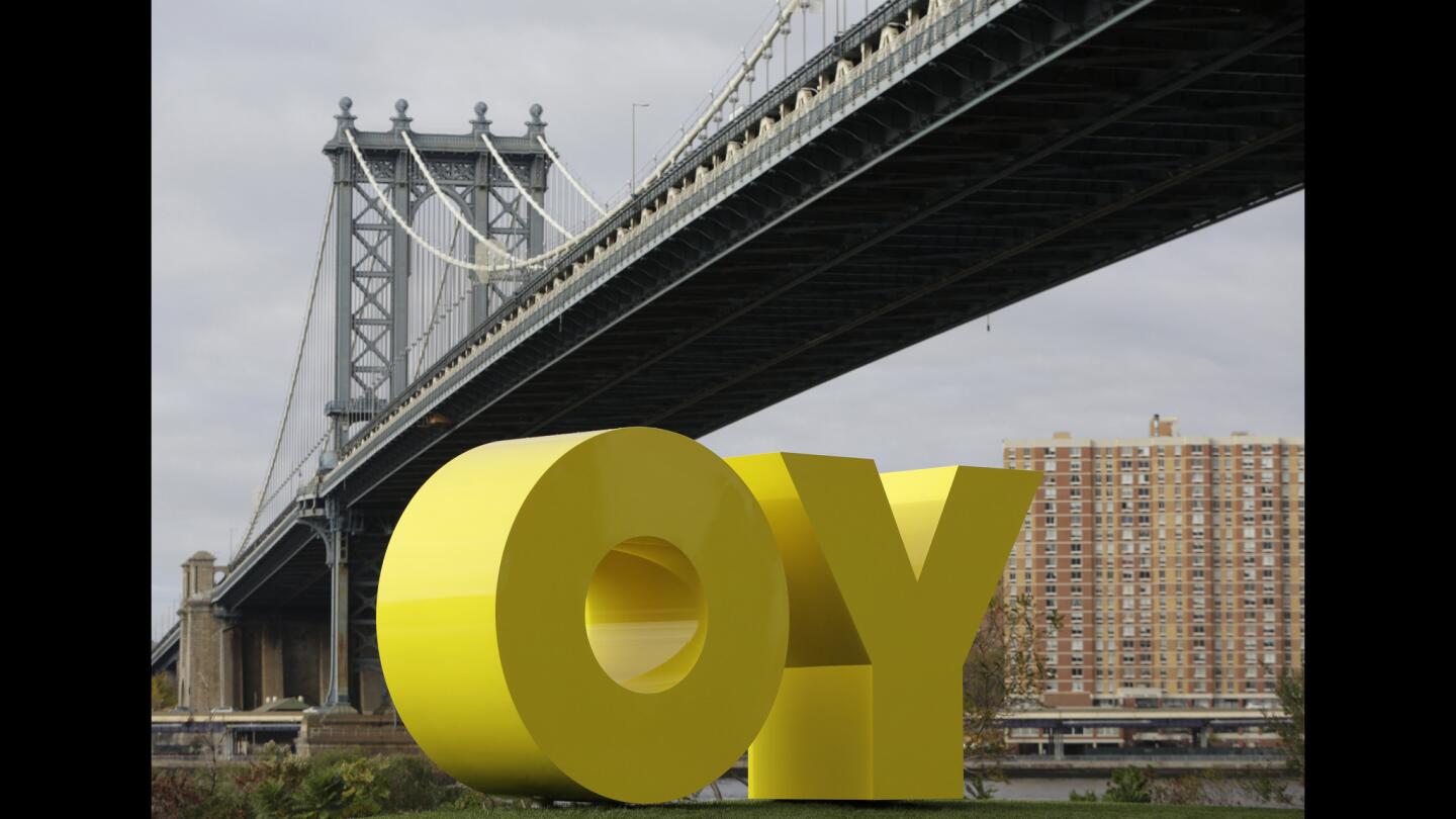 The Manhattan Bridge frames a bright yellow monumental sculpture by artist Deborah Kass in Brooklyn Bridge Park, on Wednesday, Nov. 11, 2015, in New York. When viewed from Manhattan, the sculpture reads "Yo," but when viewed from Brooklyn it spells the popular Yiddish expression "Oy." The aluminum sculpture was commissioned by Brooklyn developer Two Trees Management Company and will remain up until August 2016.