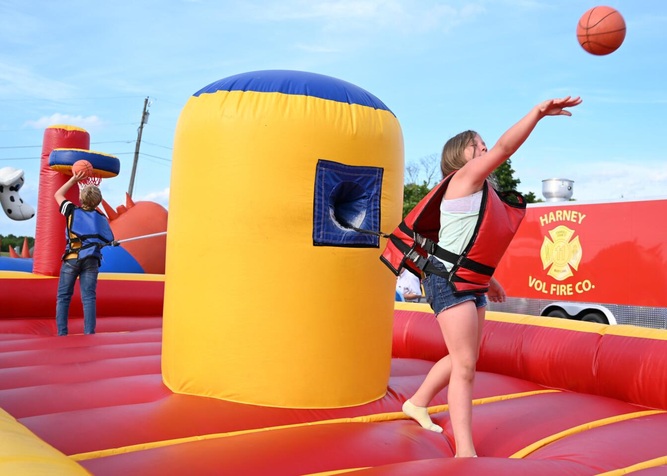Jaden Reed, right, and her cousin Braydon Kelbaugh, both of Fairfield, Pa., play a game of basketball while tethered by a bungee cord during the carnival at the Harney Volunteer Fire Company on Tuesday, June 25.