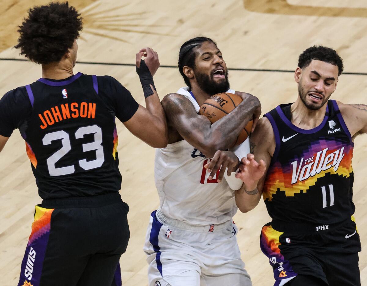 Clippers forward Paul George tries to split the defense of Suns forwards Cameron Johnson and Abdel Nader.