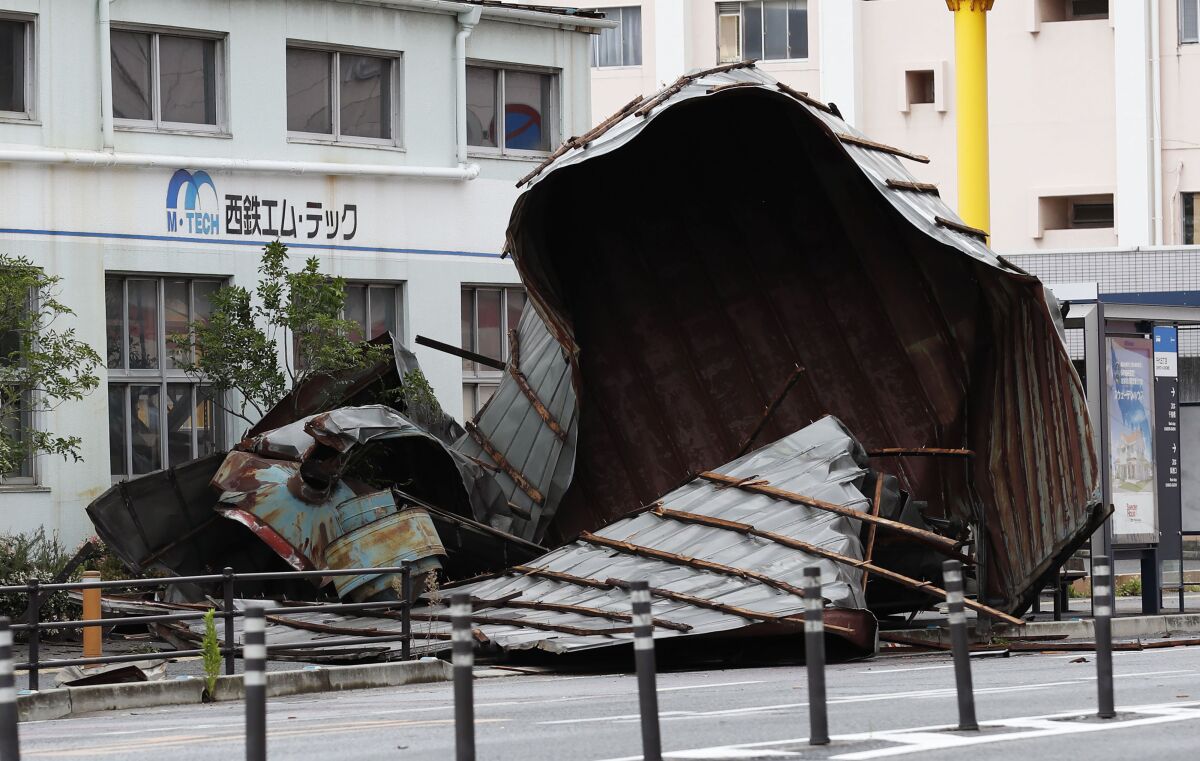 The roof of a car factory is left on sidewalk after typhoon hit Fukuoka, southwestern Japan Monday, Sept. 7, 2020. The second powerful typhoon to slam Japan in a week left people injured, damaged buildings, caused blackouts at nearly half a million homes and paralyzed traffic in southern Japanese islands before headed to South Korea.(Kyodo News via AP)
