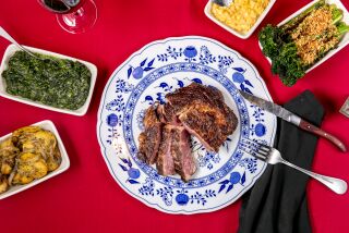 An overhead photo of steak and sides on red tablecloth at Culver City chophouse Dear John’s.