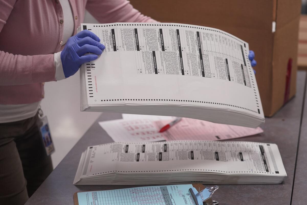 Una trabajadora electoral recoge papeletas tabuladas para ser almacenadas dentro de la Oficina de Registros