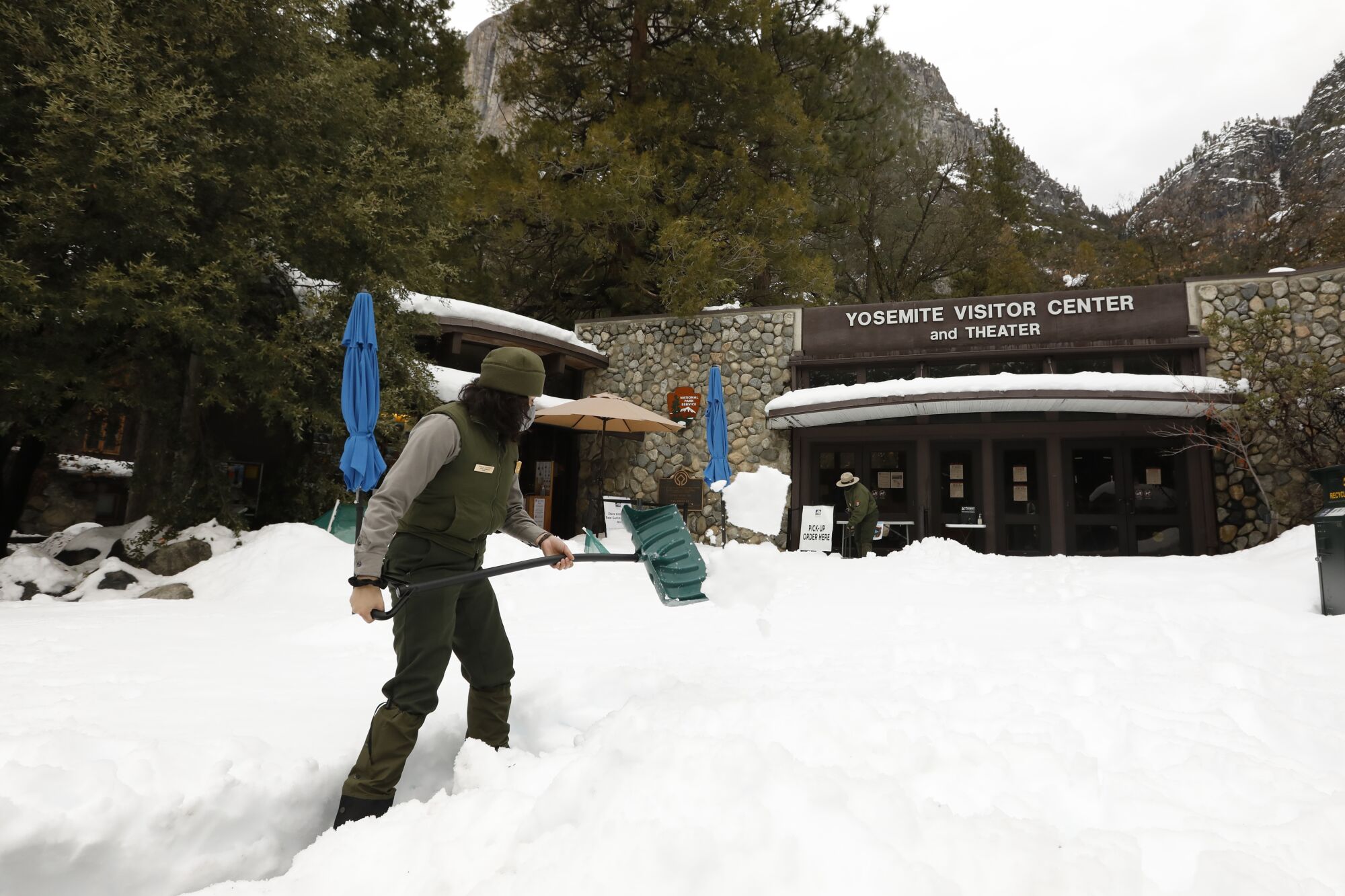 Mirella Gutierrez shovels snow in front of Yosemite Visitor Center.