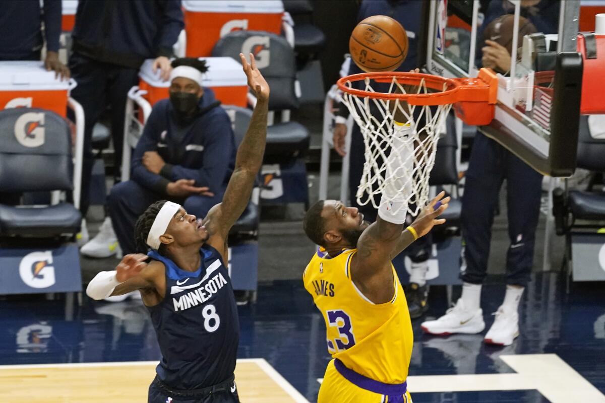 Lakers' LeBron James lays up to score as Minnesota Timberwolves' Jarred Vanderbilt looks on.