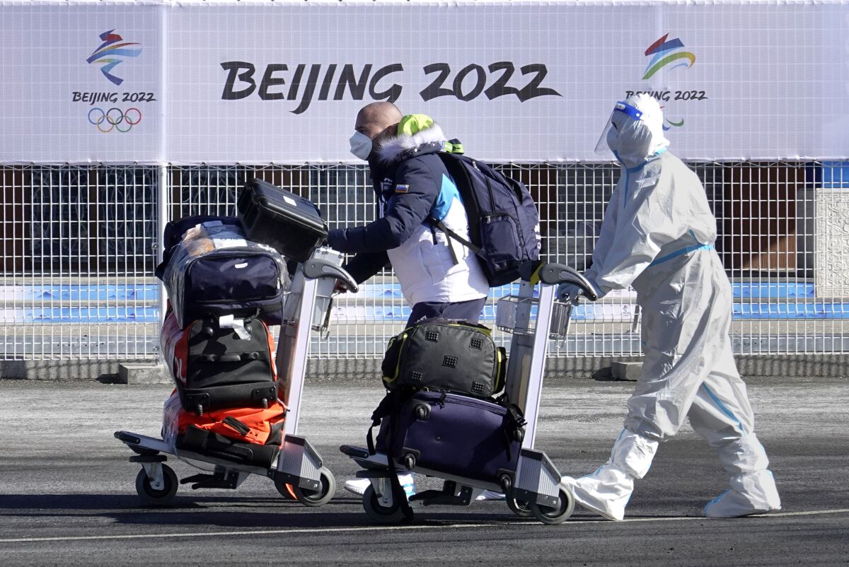 A member of Italy's Olympic delegation and a Beijing Olympics transportation worker push luggage carts.