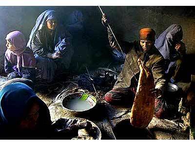 Gulbakht, in red, pulls another piece of bread out of the burner along with her workers at her bakery in Kabul, Afganistan.
