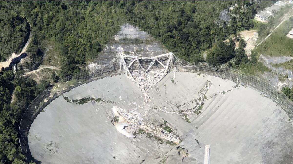 This photo provided by Aeromed shows the collapsed Radio Telescope in Arecibo, Puerto Rico, Tuesday, Dec. 1, 2020. The already damaged radio telescope that has played a key role in astronomical discoveries for more than half a century completely collapsed, falling onto the northern portion of the vast reflector dish more than 400 feet below. (Yamil Rodriguez/Aeromed via AP)