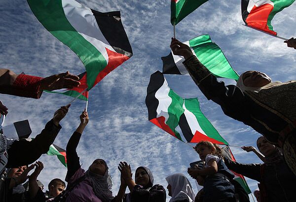 Palestinian women wave their national flag following the release of hundreds of prisoners from Israeli jails at the Palestinian Authority headquarters in the West Bank city of Ramallah.