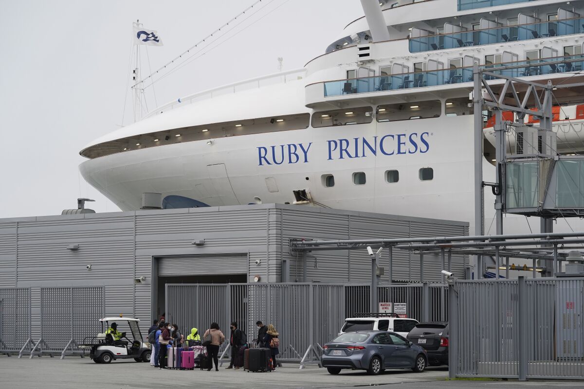 People stand on a pier outside the Ruby Princess cruise ship and wait to be picked up in San Francisco, Thursday, Jan. 6, 2021. The U.S. Centers for Disease Control and Prevention is investigating a cruise ship that docked in San Francisco on Thursday after a dozen vaccinated passengers tested positive for coronavirus. (AP Photo/Eric Risberg)