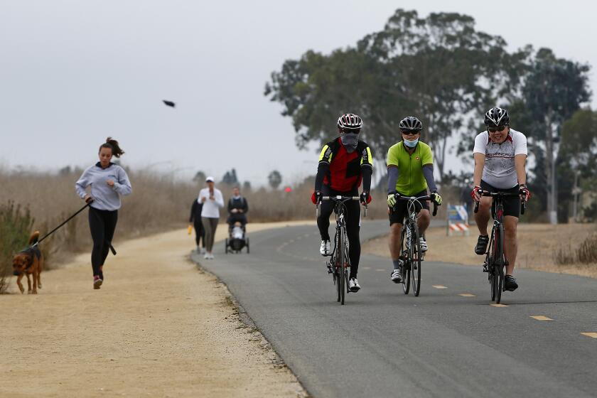 Cyclists cruise along a path at Upper Newport Bay in Newport Beach on Saturday.