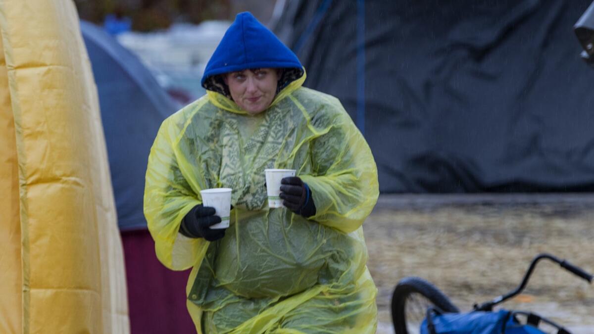 Evacuee Christa Stevens brings hot coffee to her boyfriend and uncle in the pouring rain at the makeshift tent city in Chico.