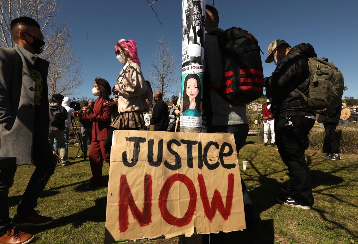 People attend a rally with a sign that reads "Justice Now" in the center.