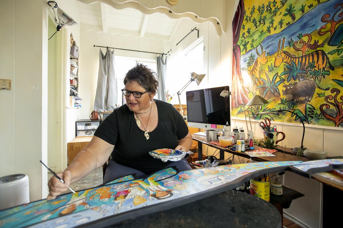 Bonnie Matthews, an artist and children's book illustrator, paints a baby whale cutout at her apartment. 