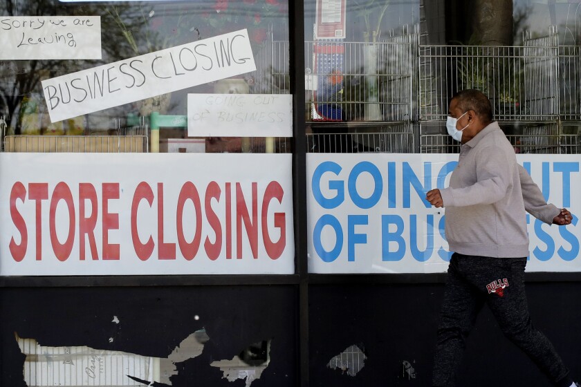 FILE - In this May 21, 2020 file photo, a man looks at signs of a closed store due to COVID-19 in Niles, Ill. U.S. layoffs surged in April revealing the deep economic hole that comes with shuttered offices, restaurants, stores and schools. (AP Photo/Nam Y. Huh, File)