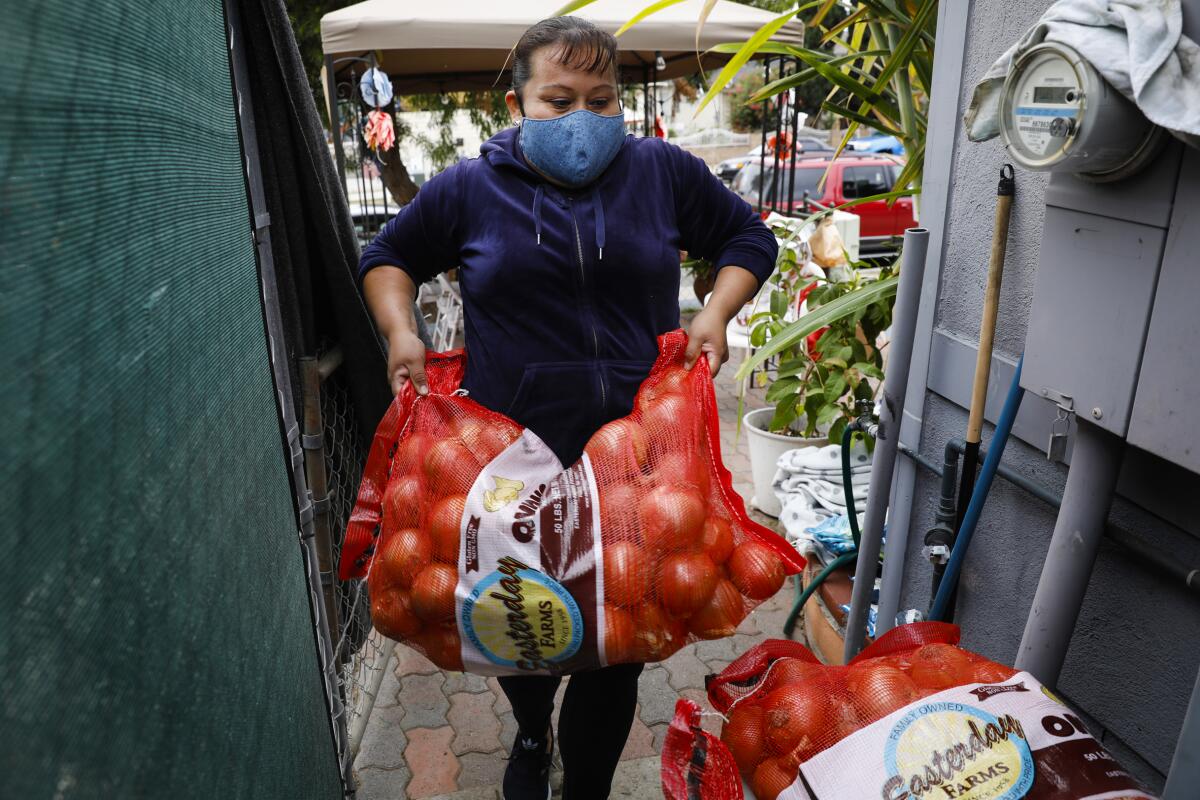 Araceli Mora, who volunteers at a free food stand, stores supplies next to a Sherman Heights home.