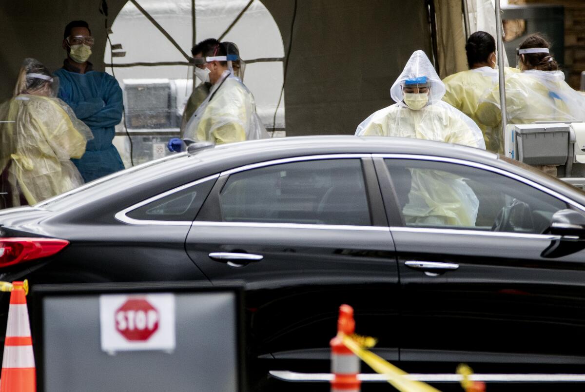 Medical personnel perform coronavirus tests at a drive-through site at St. Jude Heritage Medical Group in Yorba Linda