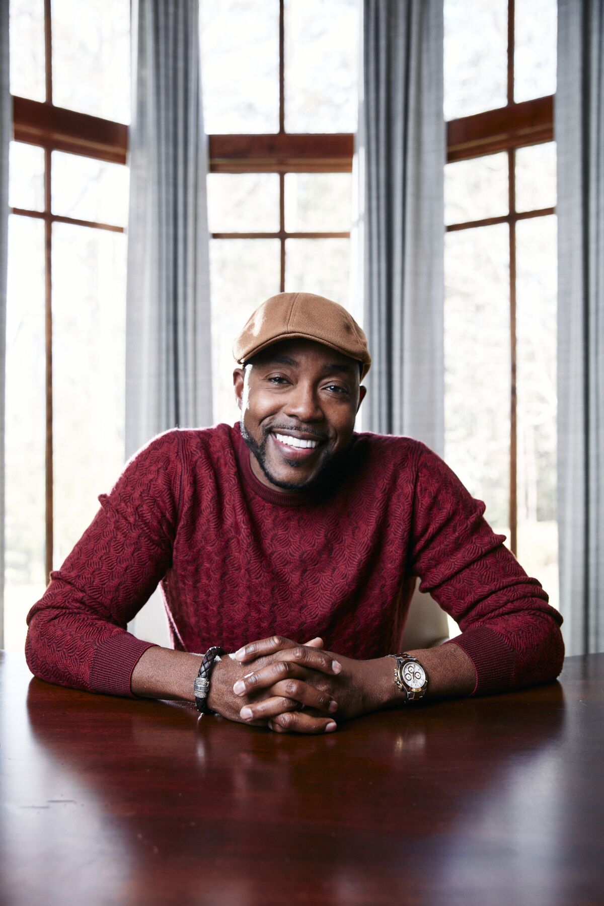 A man in a sweater and cap smiles for the camera.