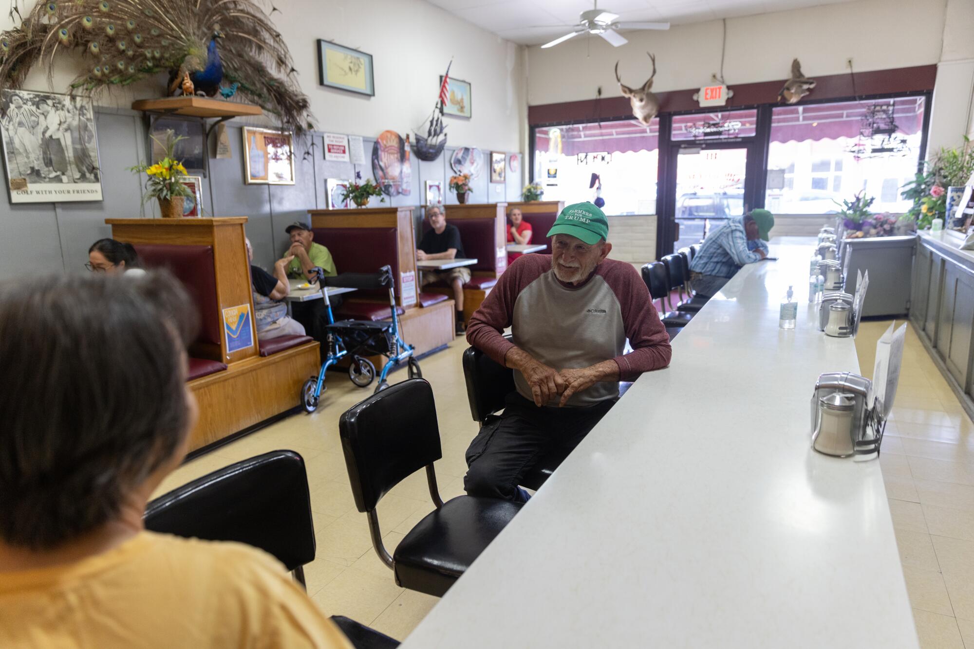 A man in a green cap sits at a white restaurant counter. 