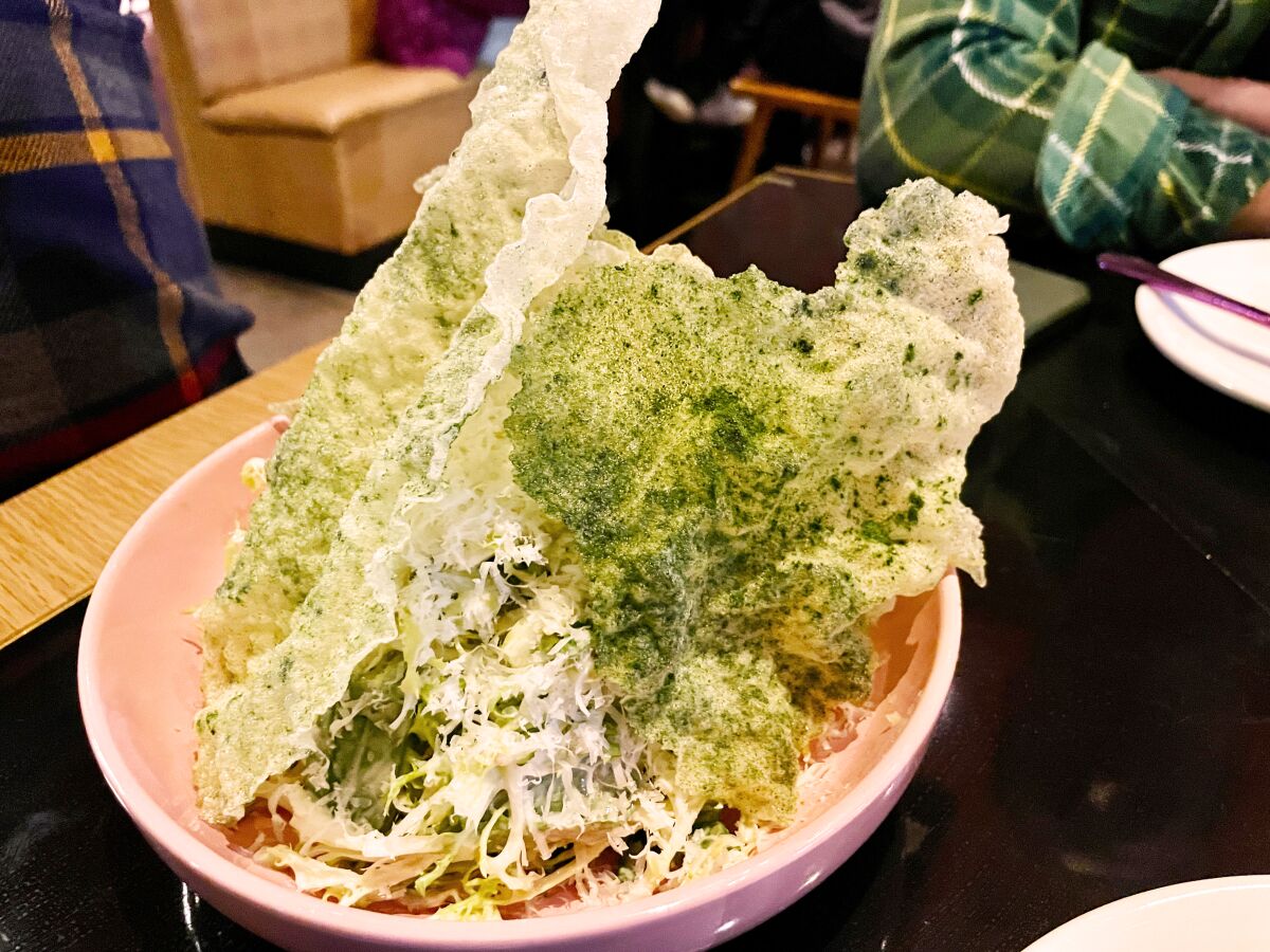 A bowl piled high with lettuce, rice paper shards and shredded cheese.