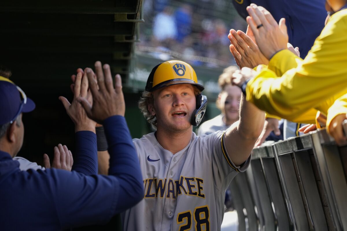 Milwaukee Brewers center fielder Joey Wiemer get high-fives in the dugout after scoring on a single by Brewers' Jesse Winker during the sixth inning of a baseball game against the Chicago Cubs Sunday, April 2, 2023, in Chicago. (AP Photo/Erin Hooley)