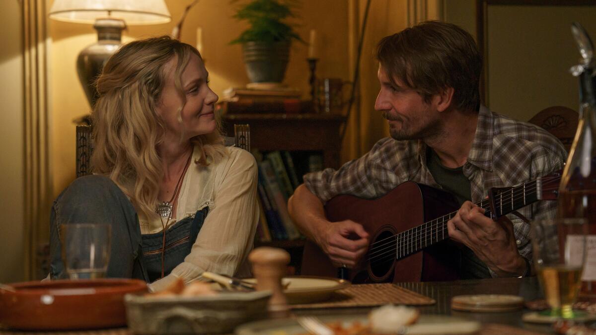 A man plays guitar for a smiling woman.
