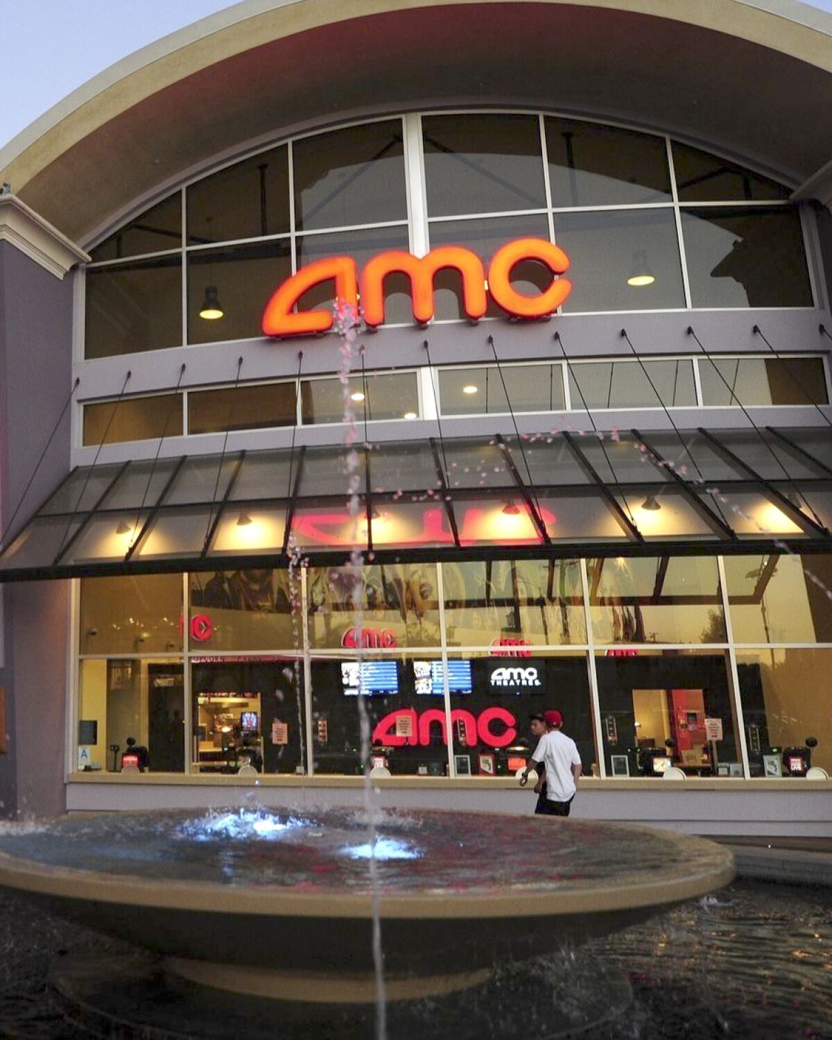 A couple watch a big screen outside movie theaters of the cinema chain AMC Entertainment in Monterey Park.