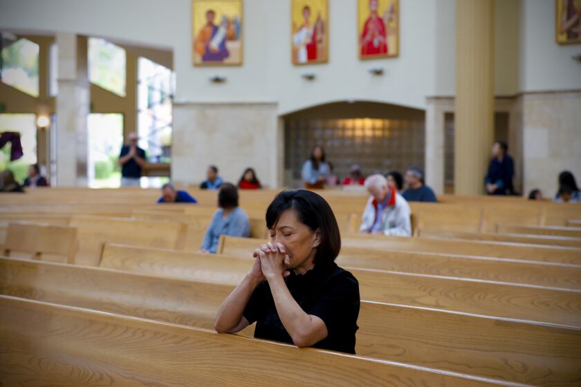 Louisa Martinez prays during Sunday mass at Corpus Christi Catholic Church in Chula Vista on March 15, 2020. Because of the statewide cancellation of gatherings over 250, the Diocese of San Diego is canceling public masses effective March 16th. The 9:00am mass at Corpus Christi typically would draw about 800 parish members, however on Sunday they had about 150 members.